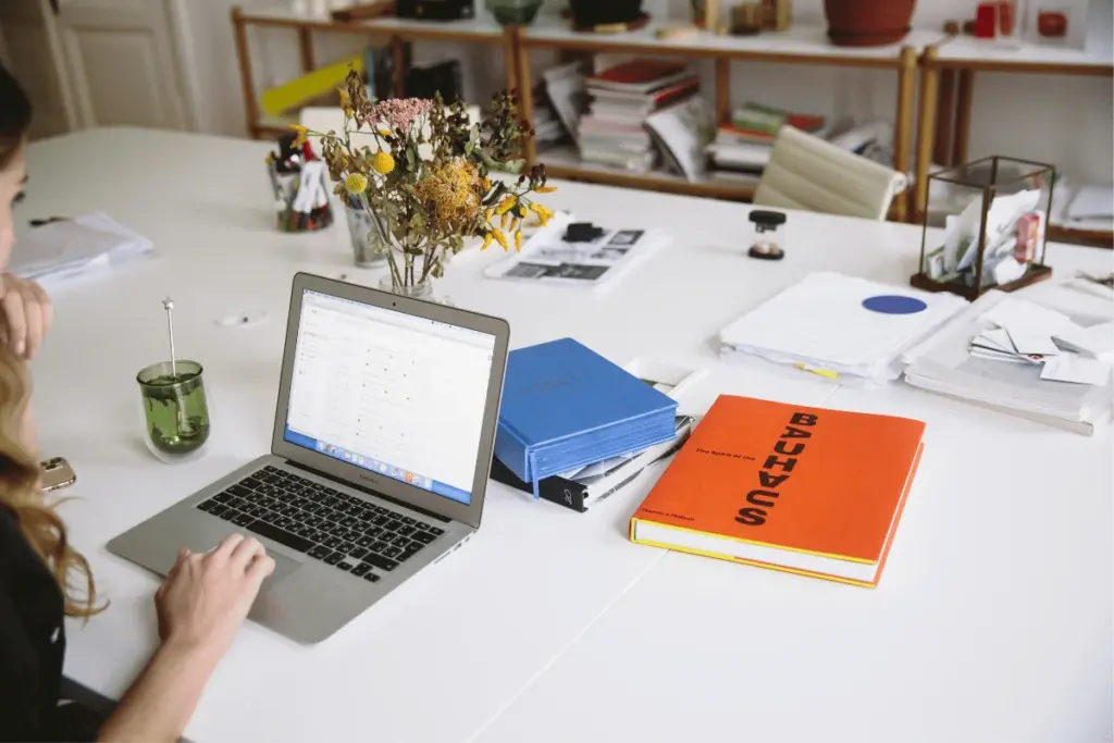 Laptop on a desk with documents and office supplies showing a workspace setup.