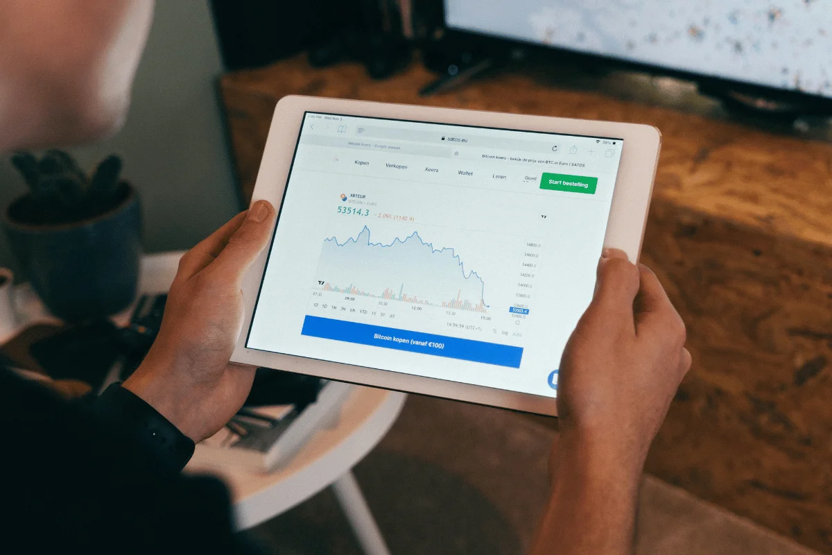 Person analyzing market data on a tablet with a performance chart.
