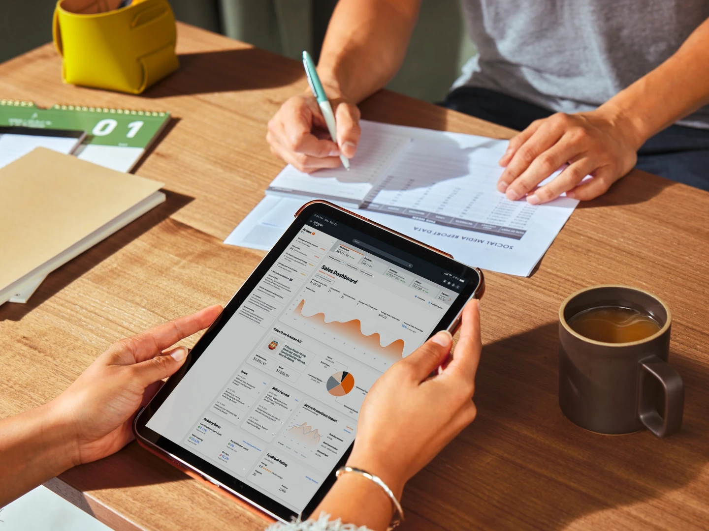 Person analyzing sales dashboard on a tablet and writing amazon agency cost